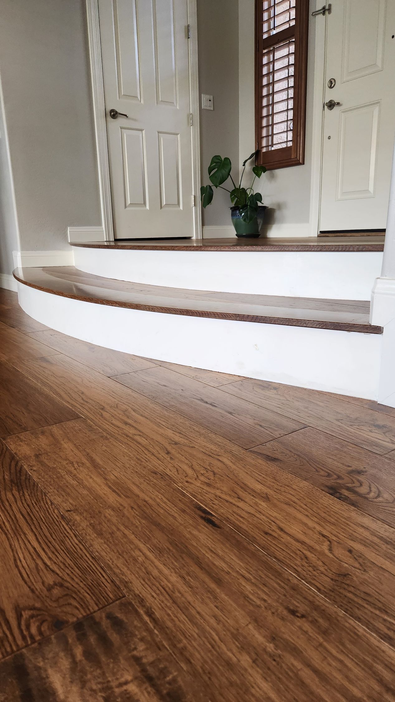 A wooden floor with white stairs in a living room.
