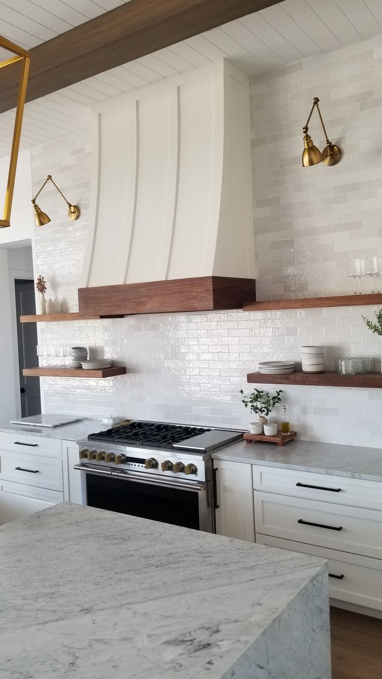 A kitchen with white cabinets, a stove, and a hood.