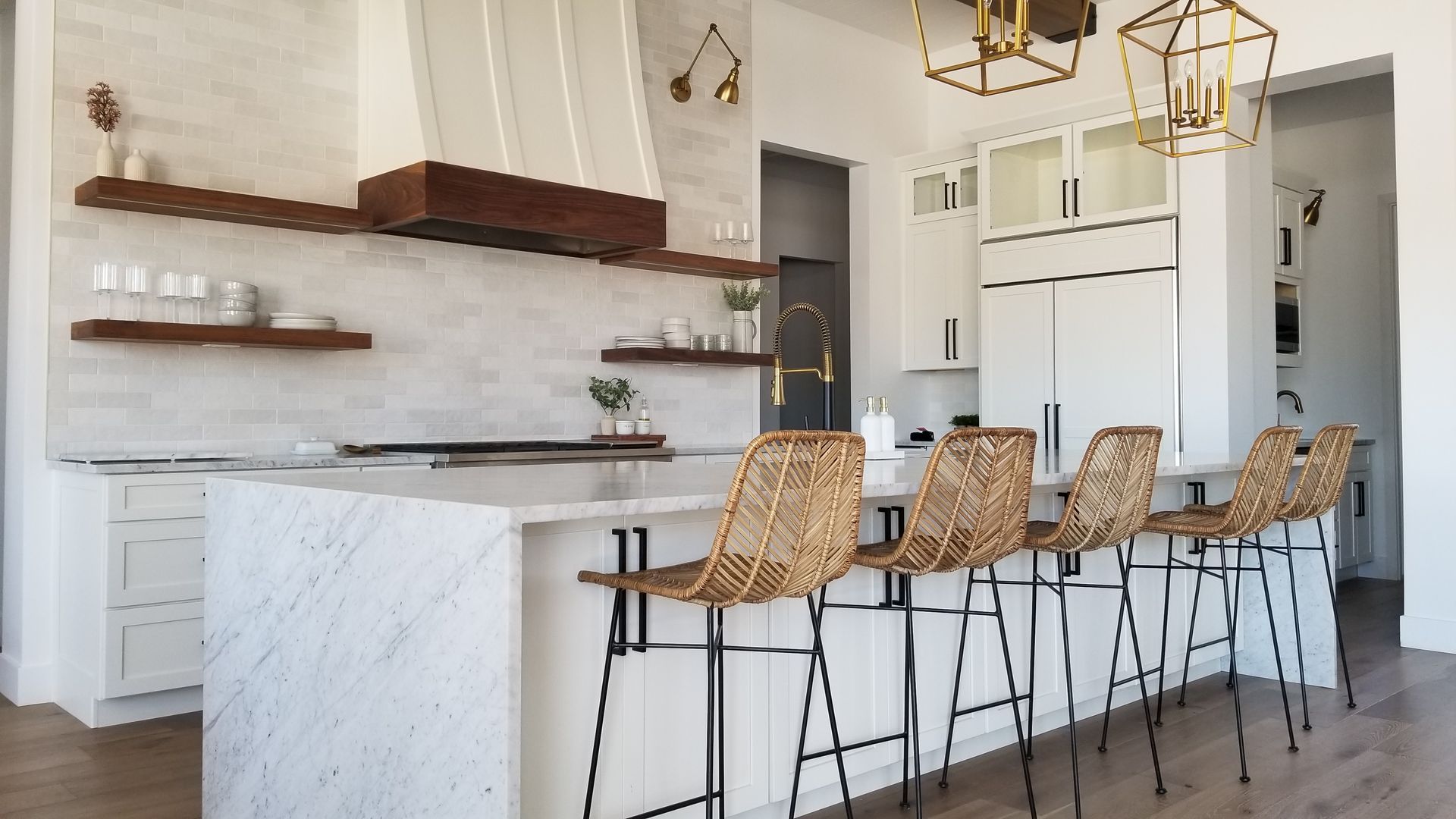 A kitchen with a large island and wicker bar stools.