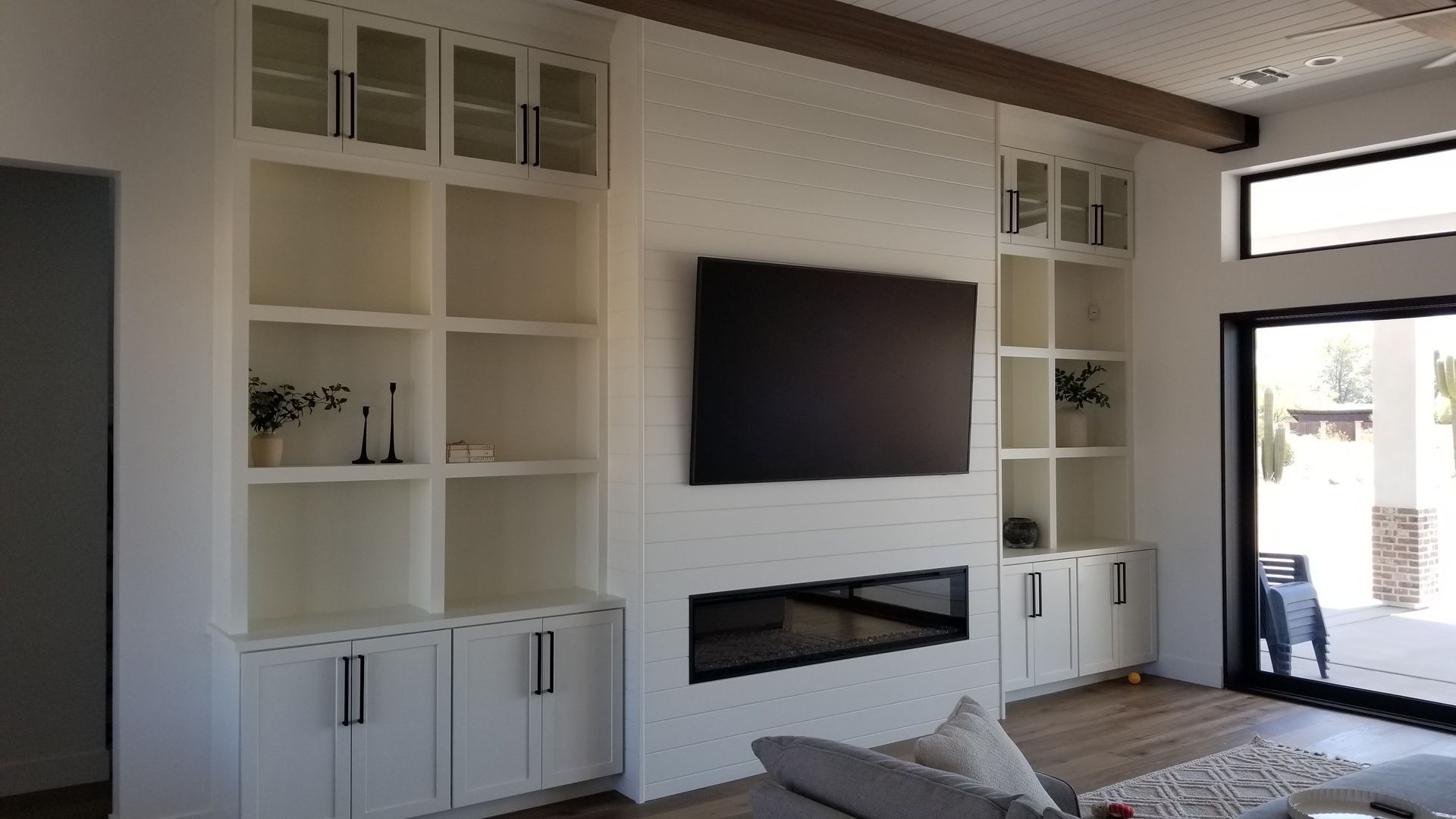 A living room with a fireplace and a flat-screen tv on the wall.