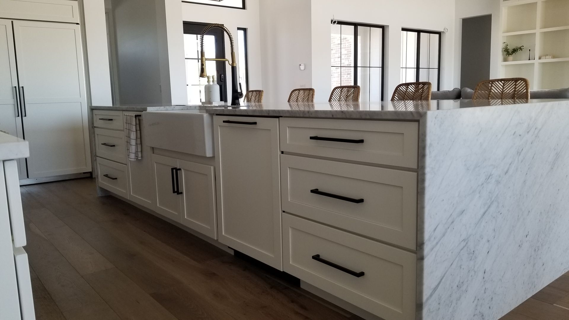 A kitchen with white cabinets black handles and a large island.