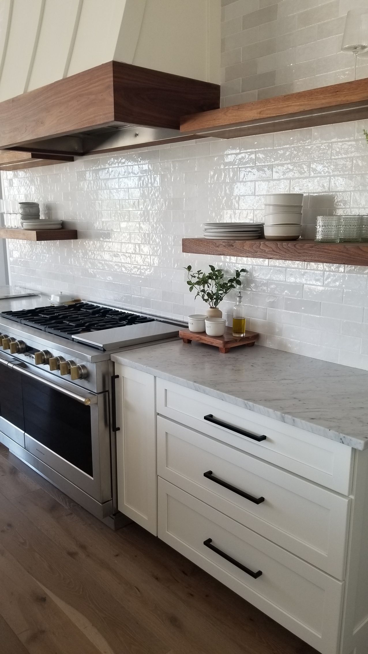 A kitchen with white cabinets, a stove, and a shelf.