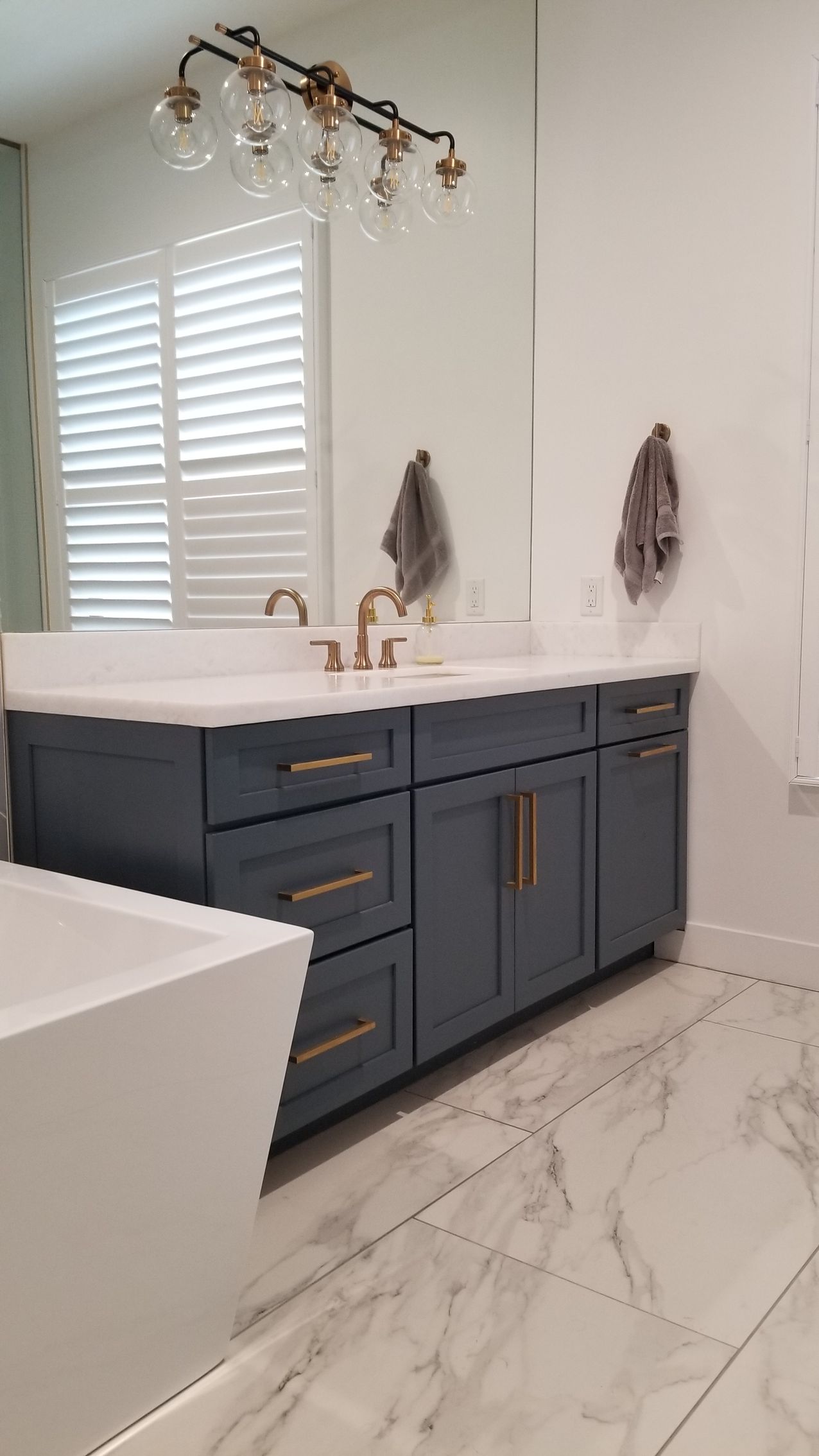 A bathroom with two sinks, a tub, and a mirror.