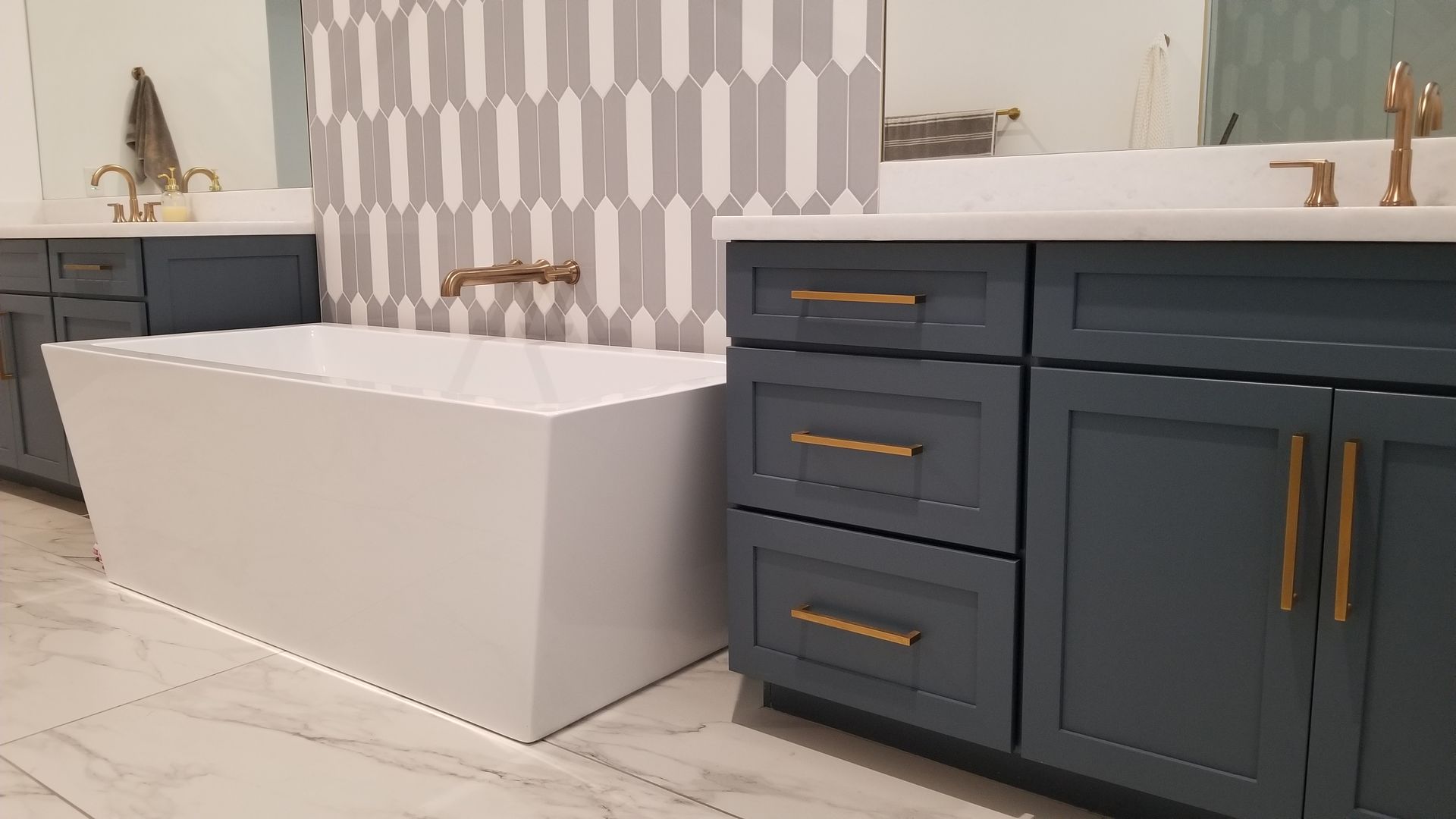 A bathroom with two sinks, a bathtub, and blue cabinets.