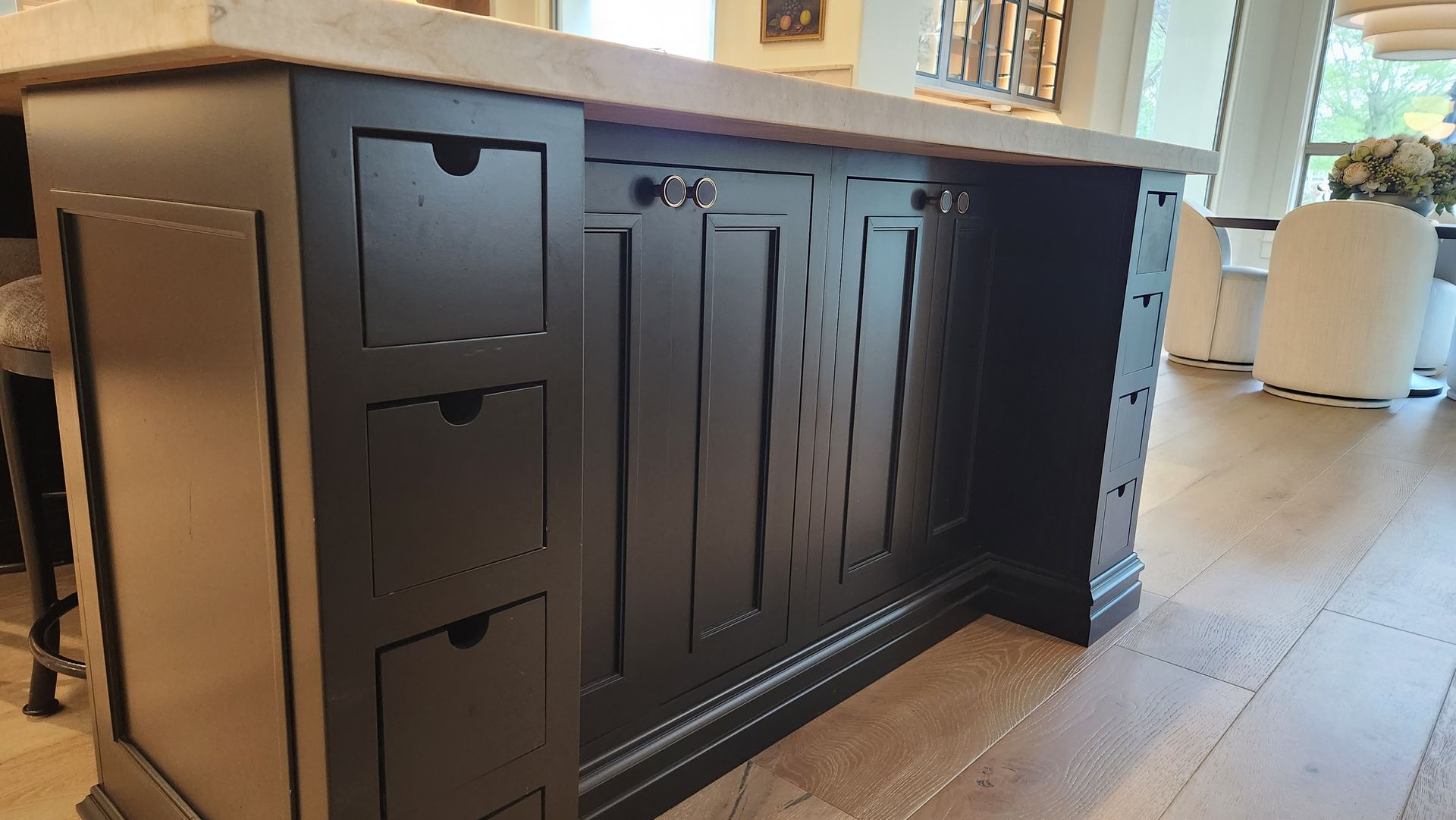 A kitchen island with black cabinets and drawers on a wooden floor.