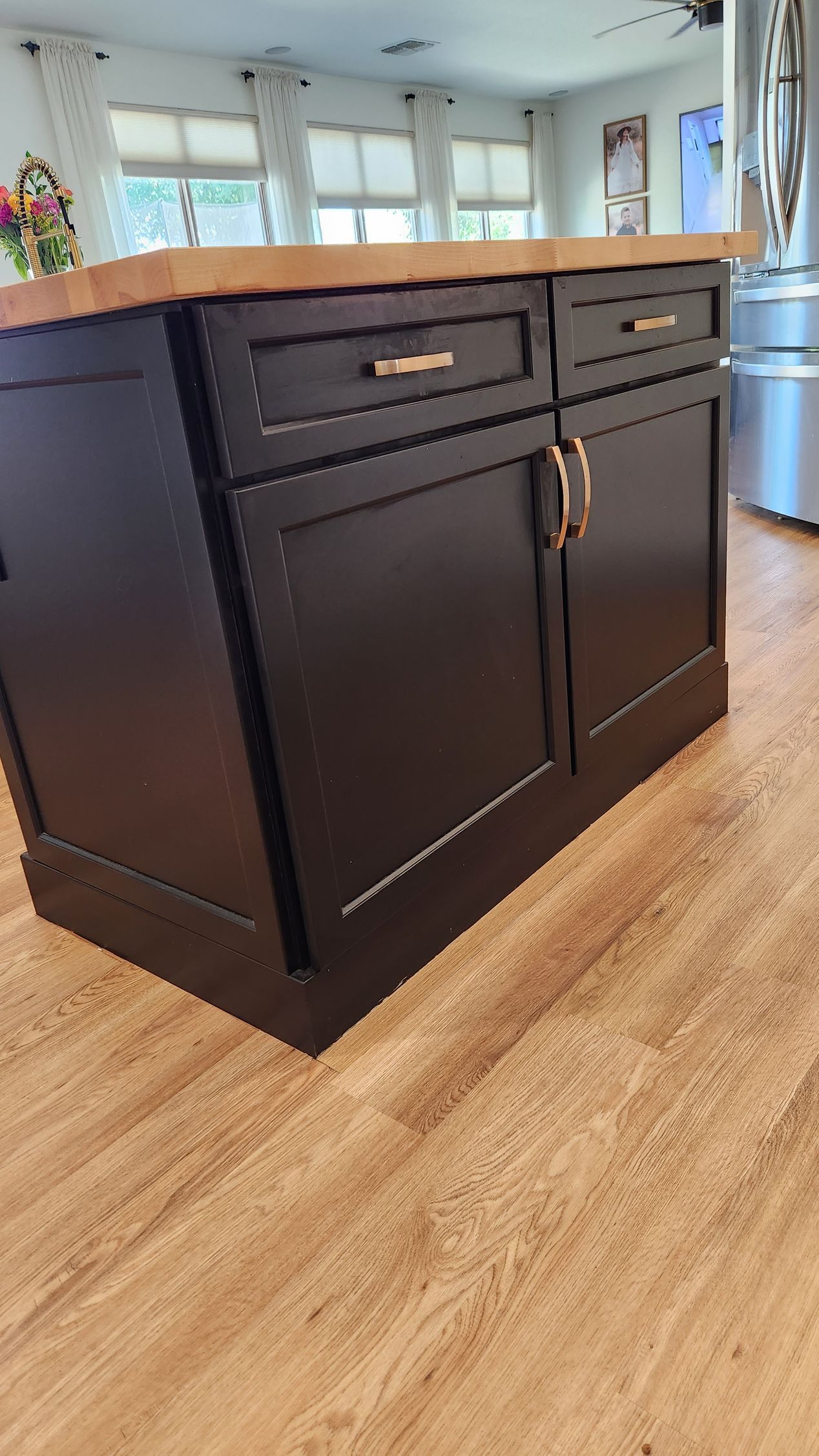 A kitchen island with black cabinets and a wooden countertop.