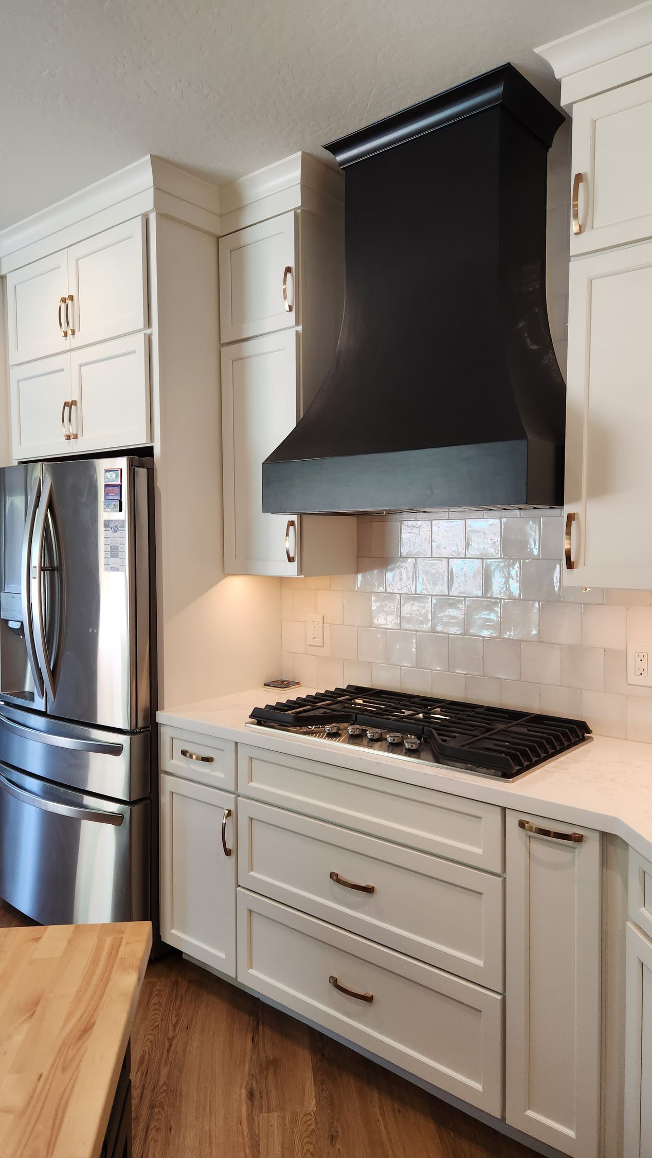 A kitchen with white cabinets, stainless steel appliances, a stove top oven, and a refrigerator.