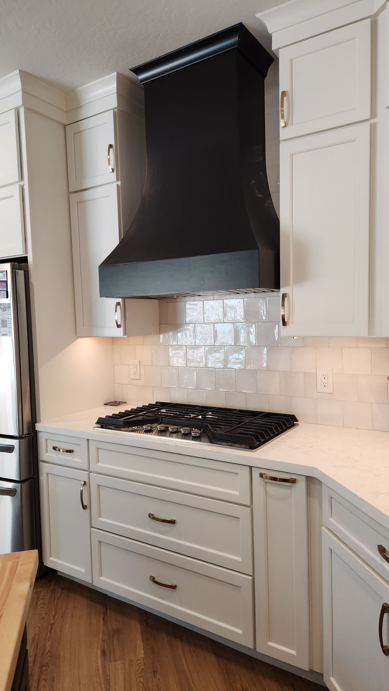 A kitchen with white cabinets and a black stove hood.
