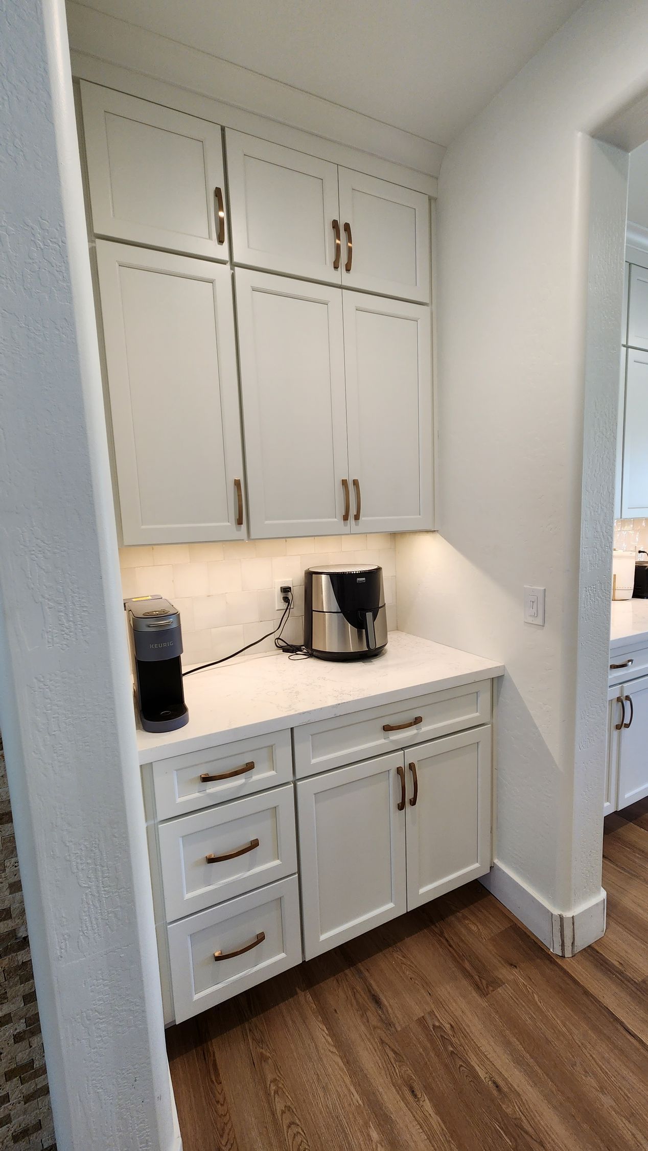 A kitchen with white cabinets and a coffee maker on the counter.
