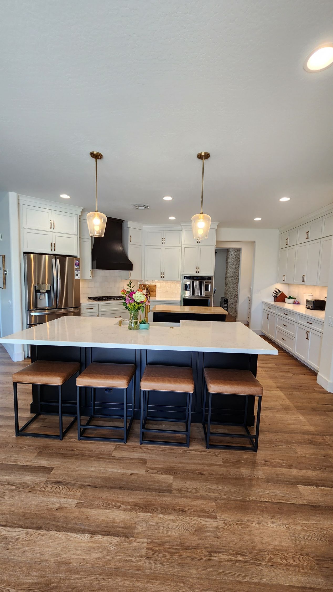 A kitchen with a large island and stools in it.