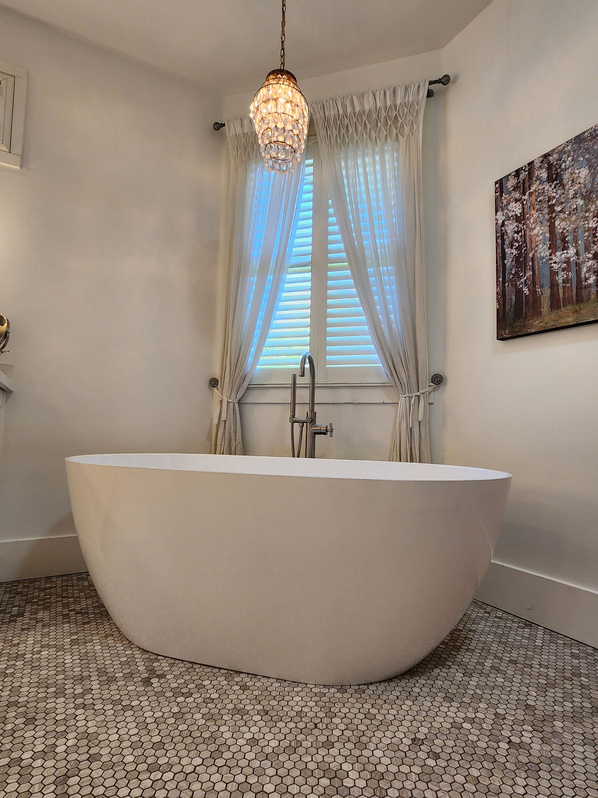 A bathroom with a bathtub and a chandelier hanging from the ceiling.