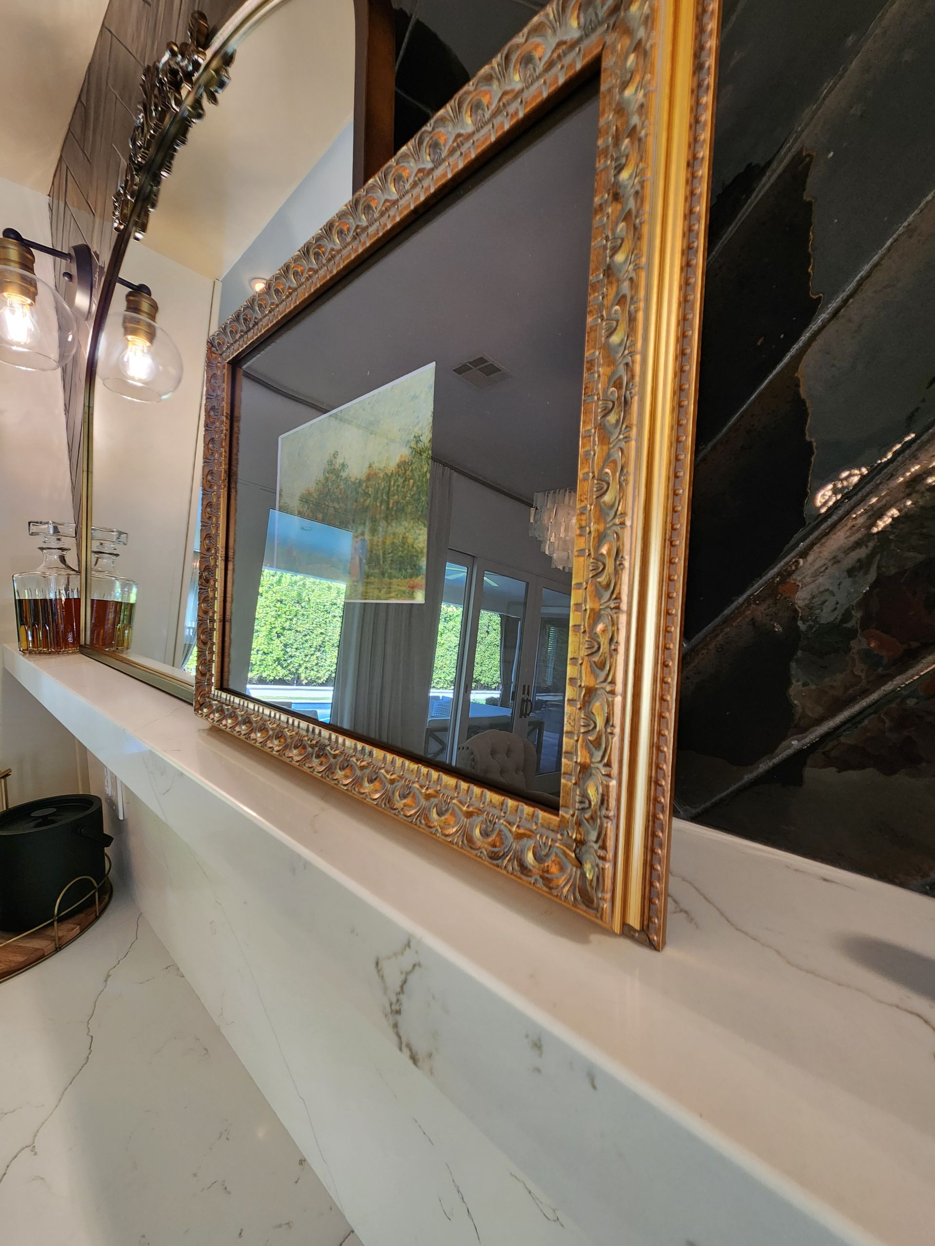 A picture in a gold frame is hanging on a shelf.