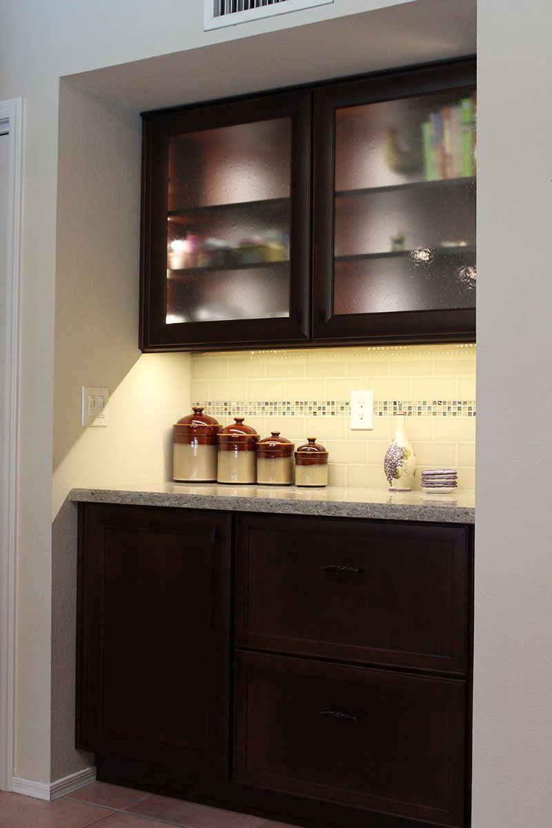 A kitchen with wooden cabinets and glass doors