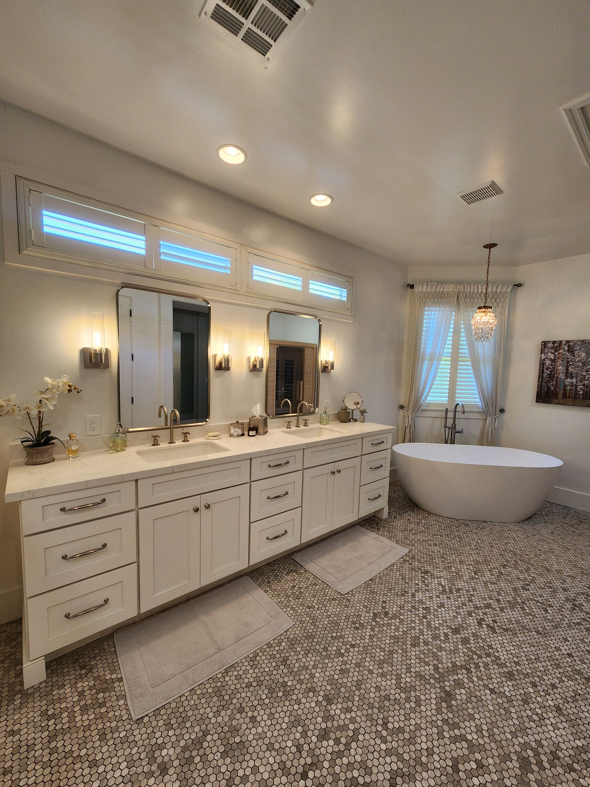 A bathroom with two sinks, a tub, and a mirror.