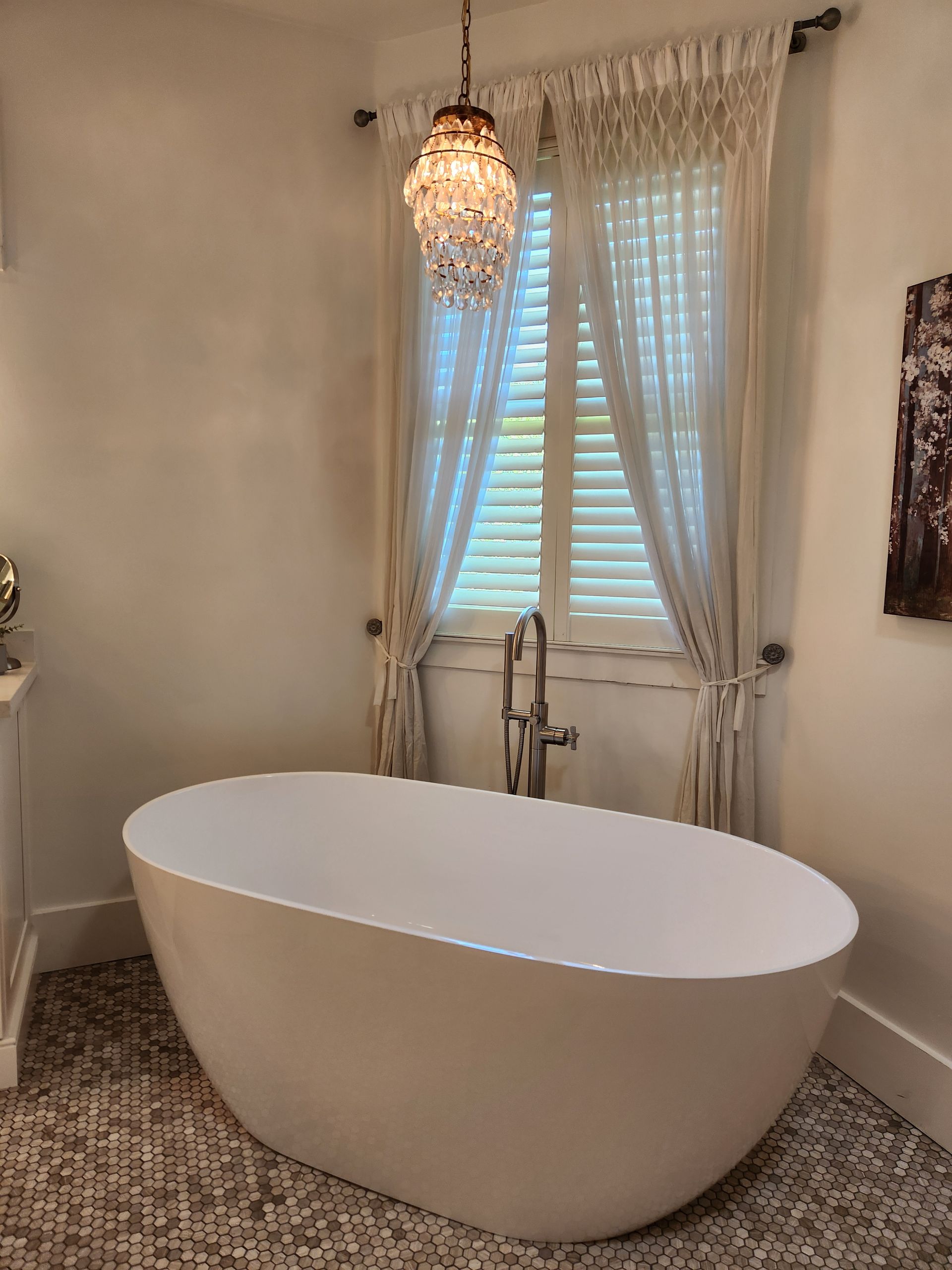 A bathroom with a bathtub and a chandelier hanging from the ceiling.
