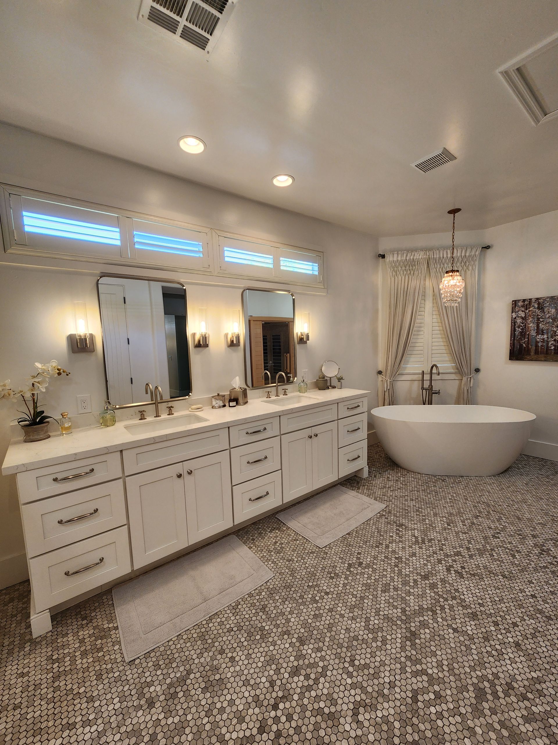 A bathroom with two sinks, a tub, and a mirror.