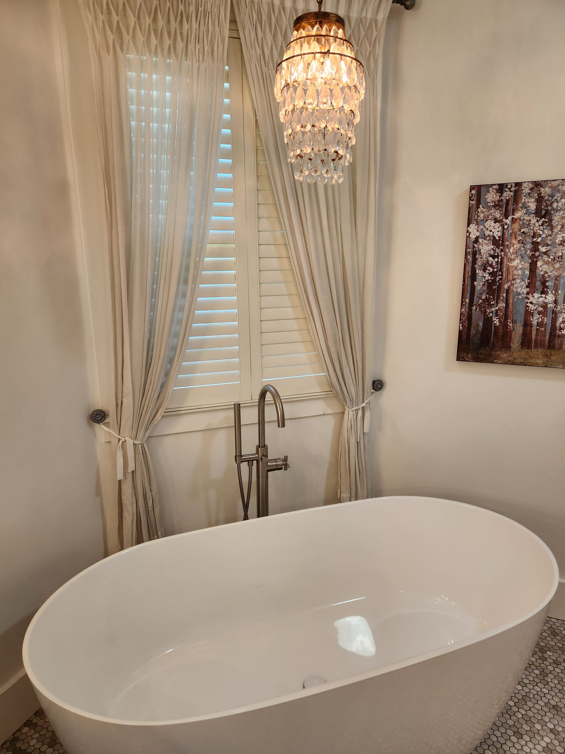A bathroom with a bathtub and a chandelier hanging from the ceiling.