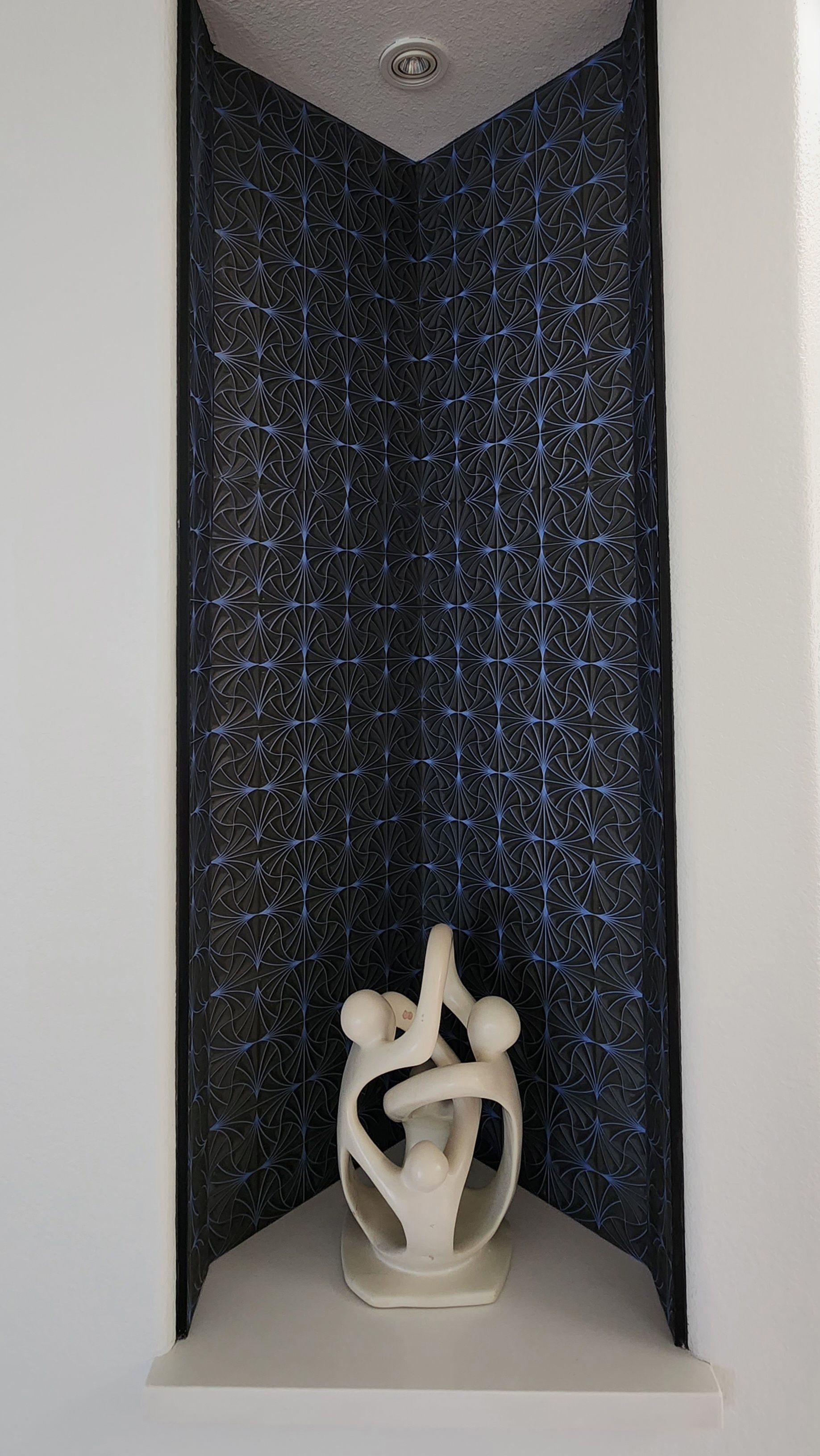 A statue of a couple standing next to each other in a corner of a room.