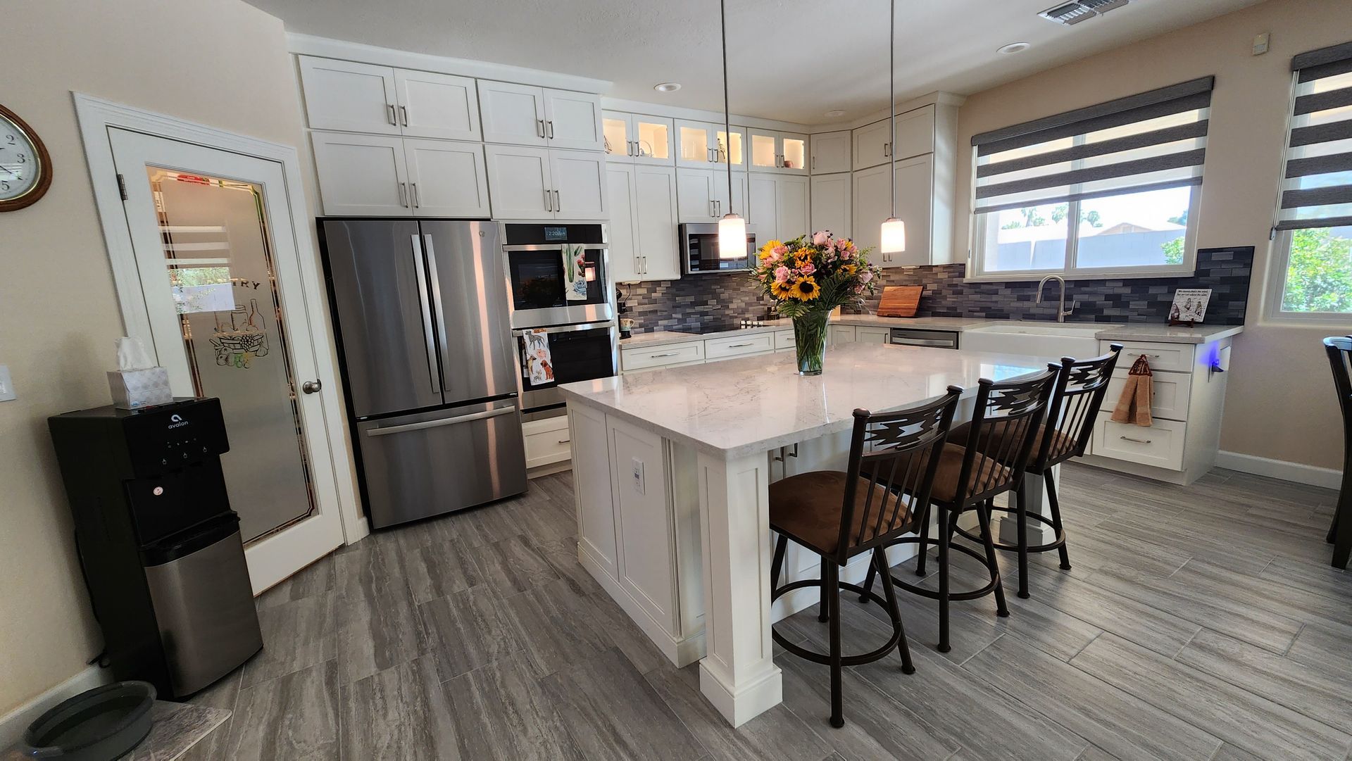 A kitchen with a large island, stainless steel appliances, white cabinets, and a refrigerator.