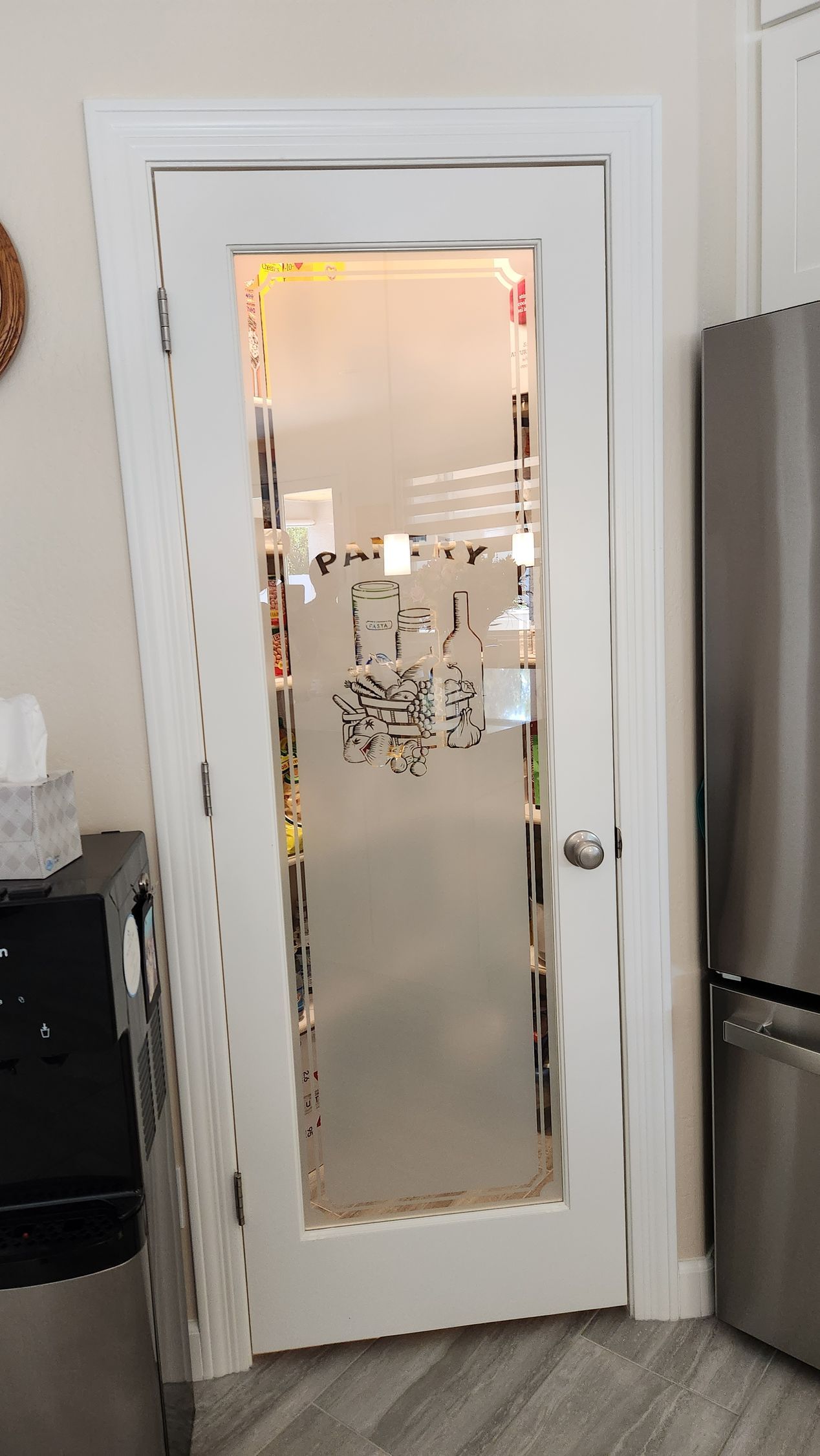 A white door with a frosted glass window in a kitchen next to a refrigerator.