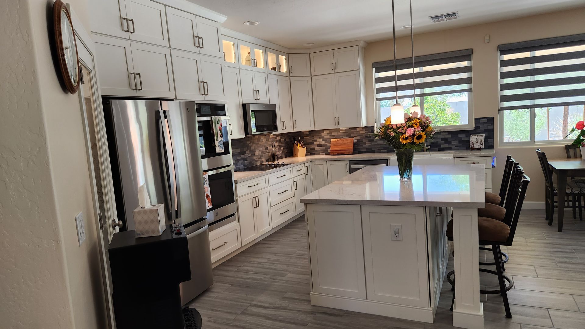 A kitchen with white cabinets, stainless steel appliances, and a large island.