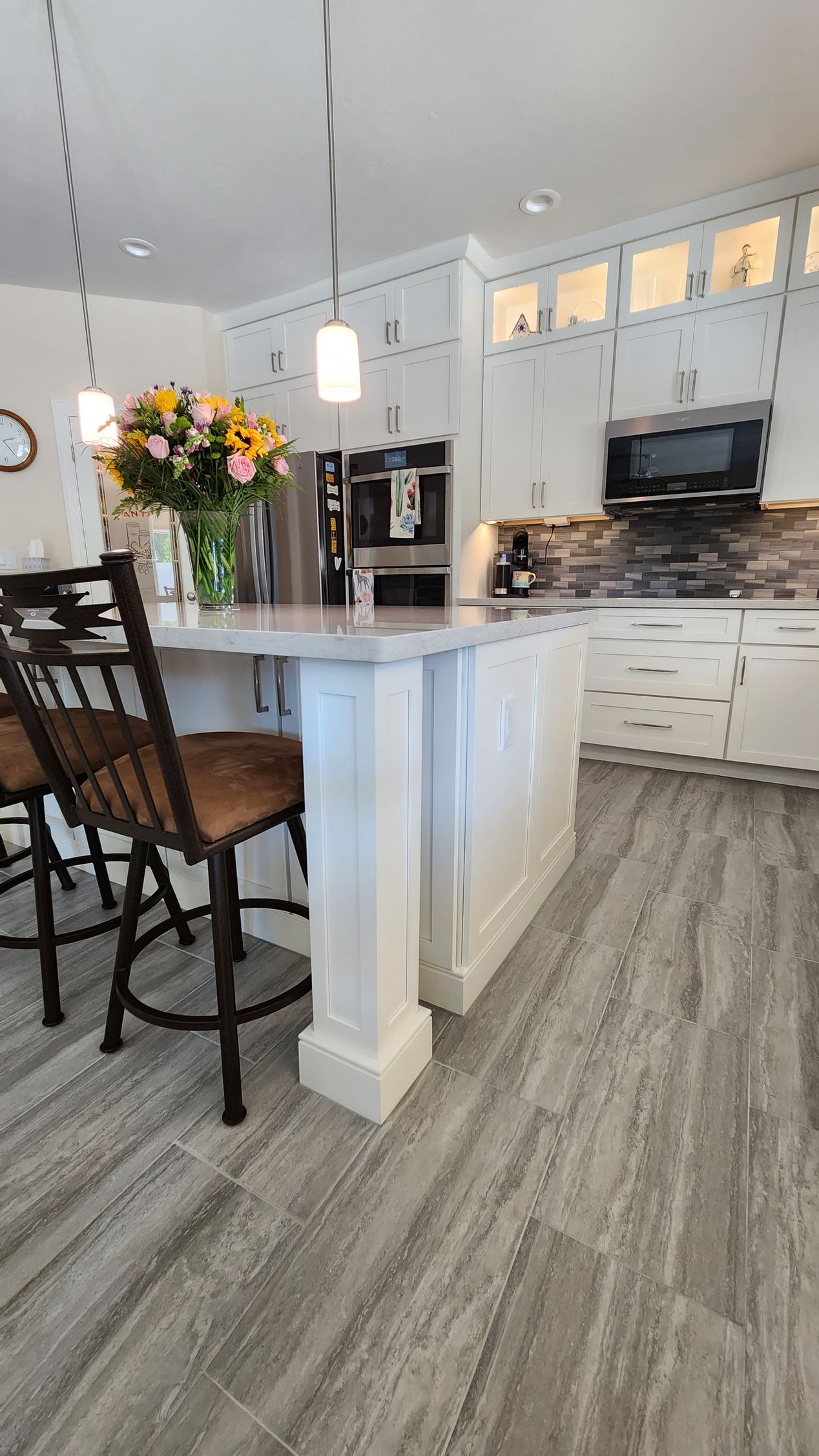 A kitchen with a large island and a vase of flowers on the counter.