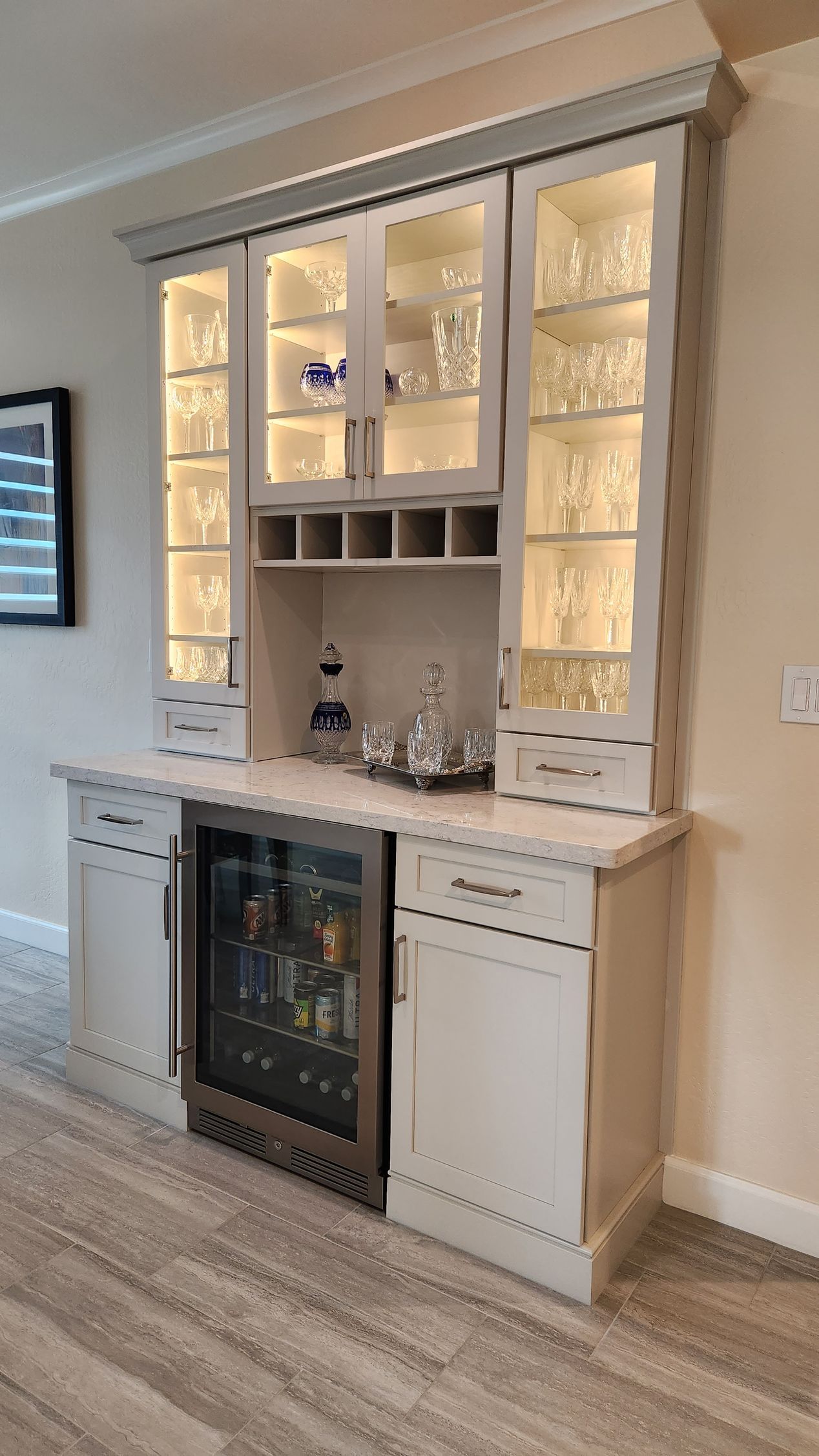 There is a bar in the middle of the room with a refrigerator.
