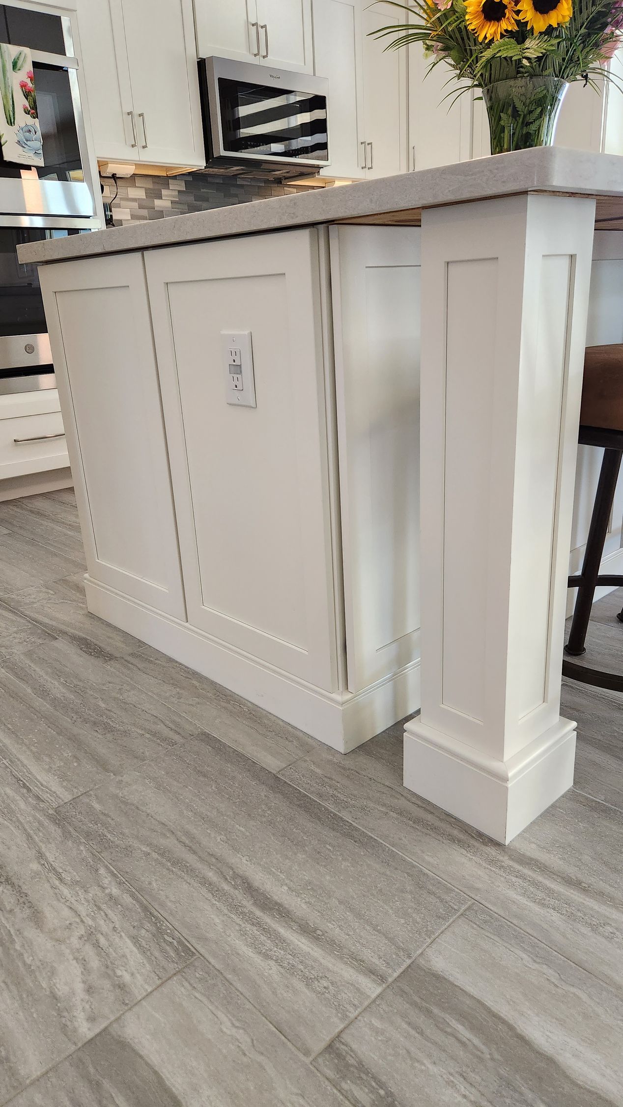 A kitchen island with a vase of sunflowers on top of it.