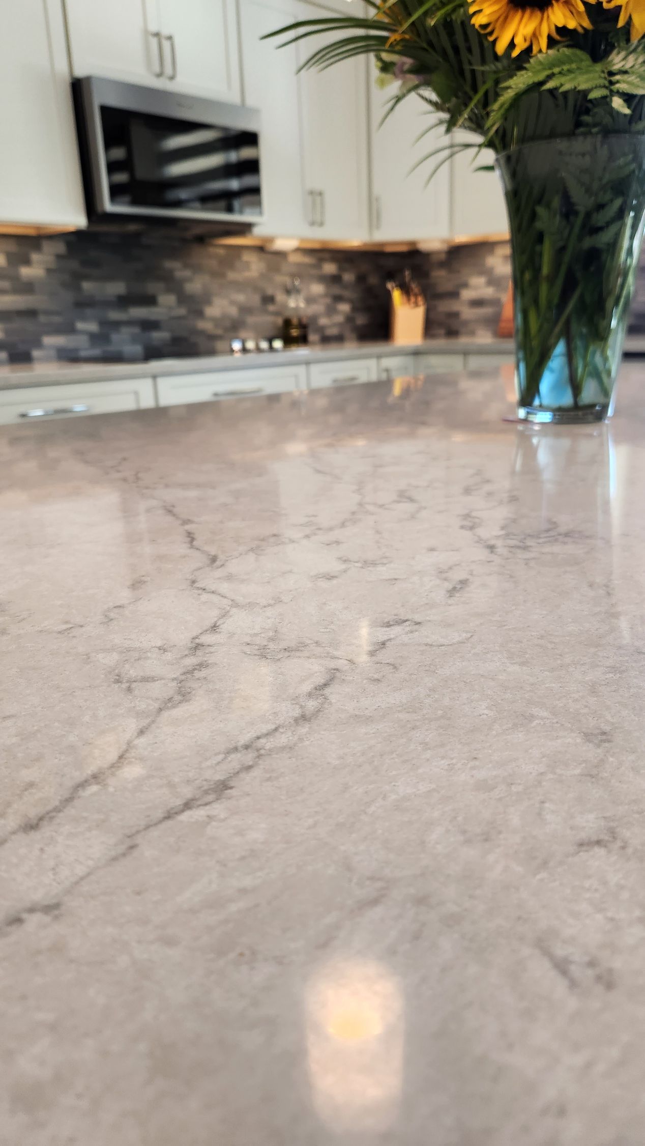 A kitchen counter with a vase of flowers on it.