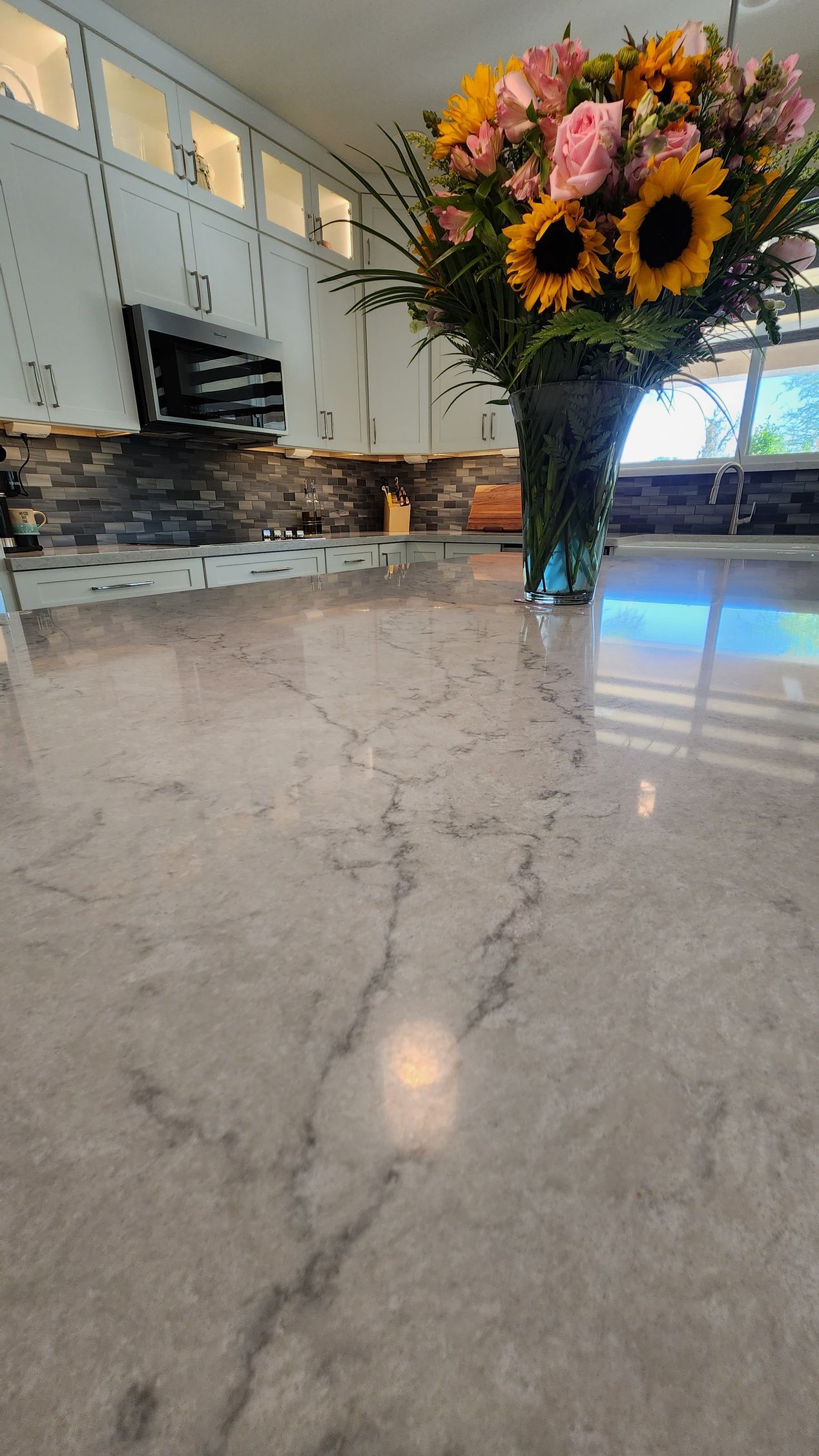 A vase of flowers is sitting on a counter in a kitchen.