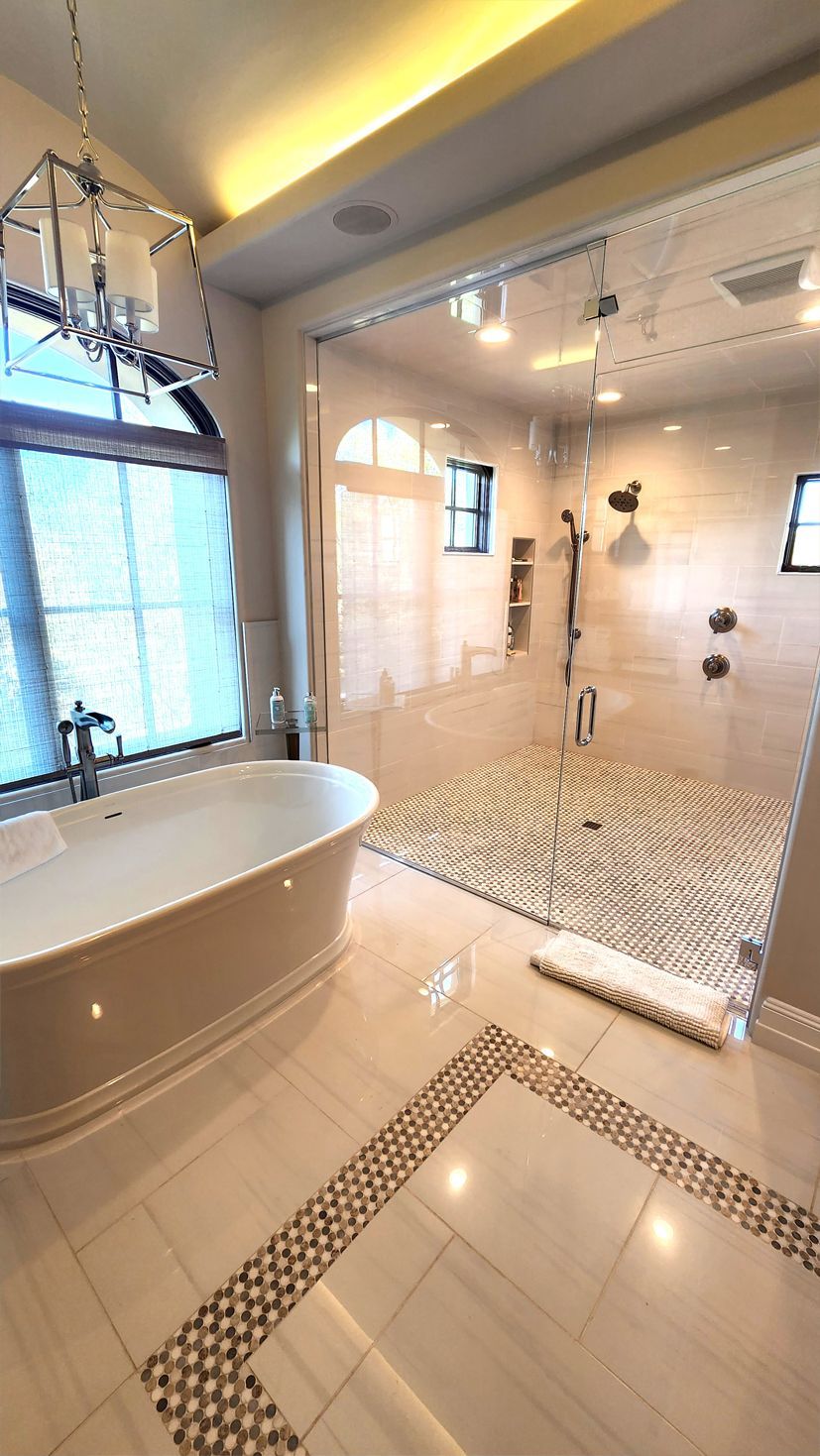 A bathroom with a tub, a shower, and a window.