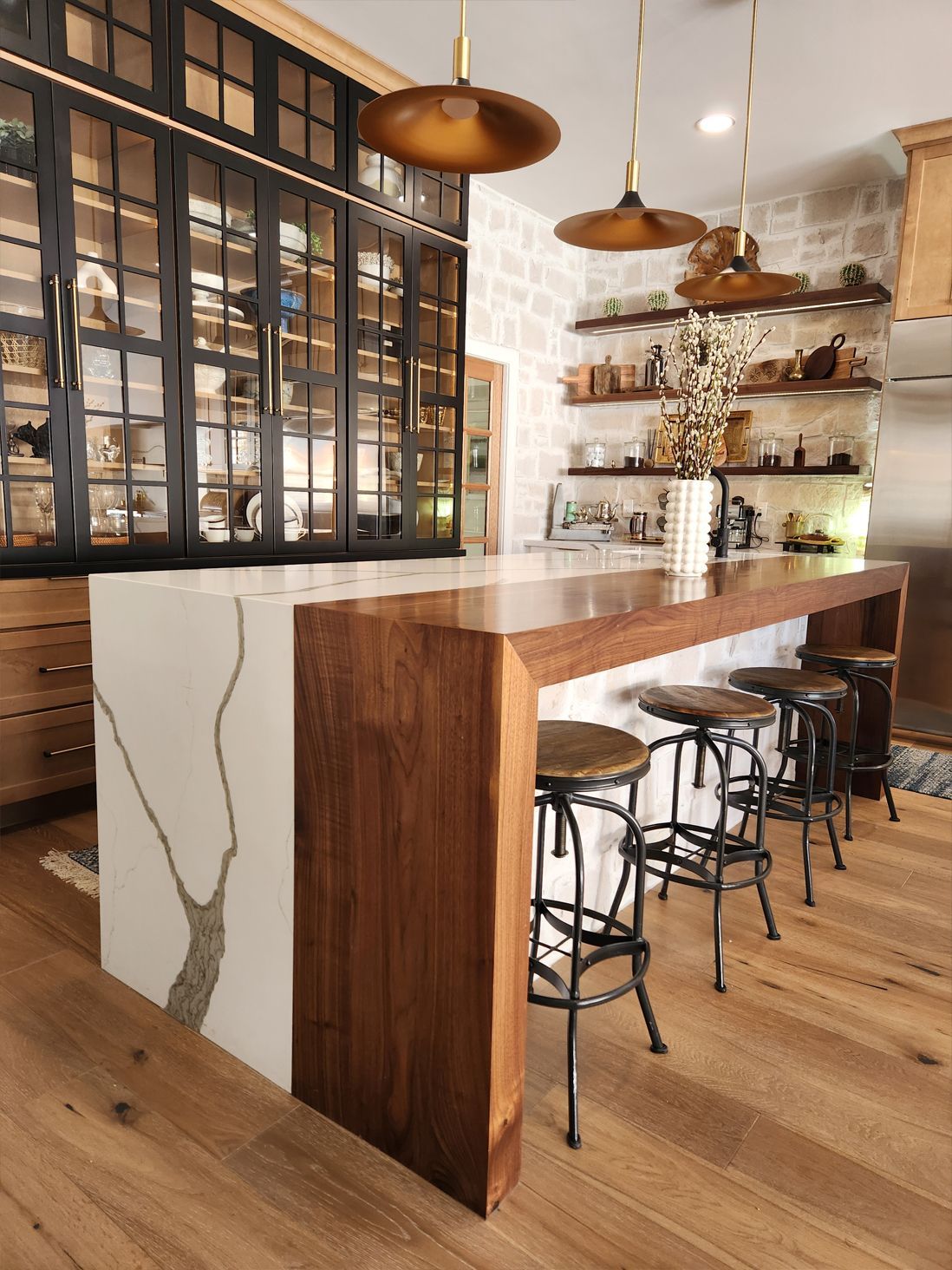 A kitchen with a long wooden counter top and stools.