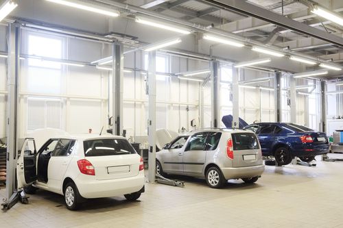 Bright car service bay with several parked cars under overhead lights