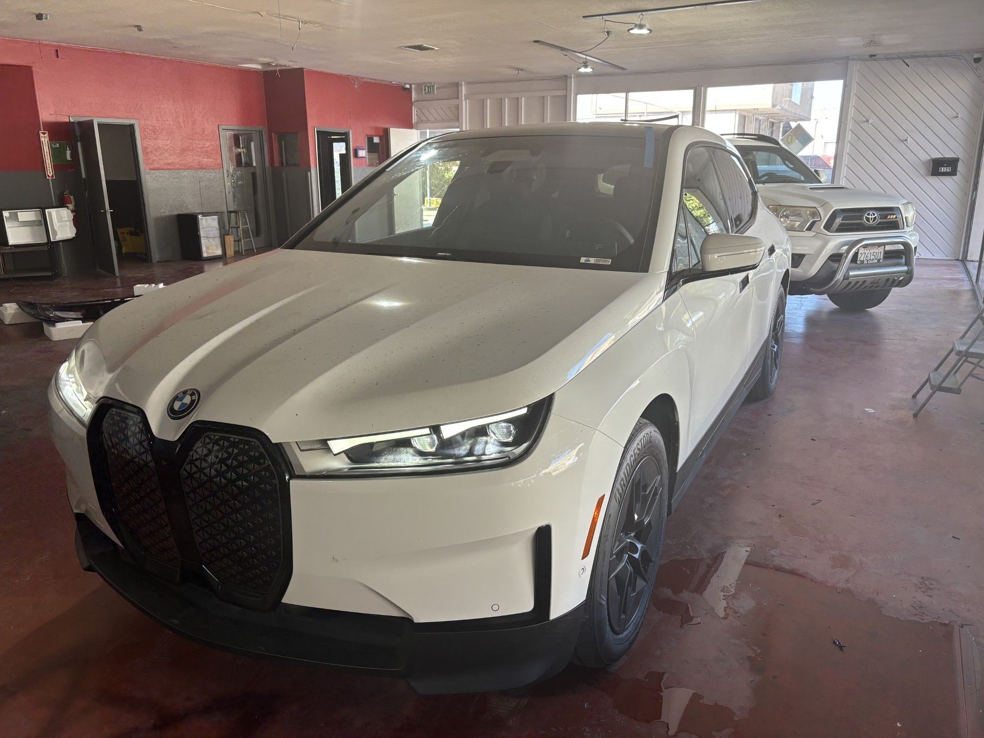White BMW sedan parked indoors in a garage with another car behind it