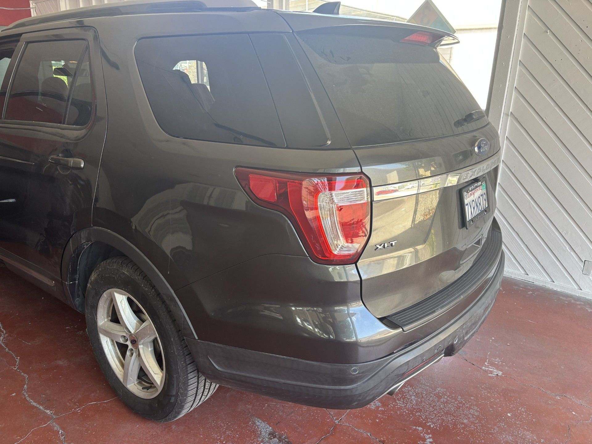 Black SUV parked in a covered driveway, rear three-quarter view.