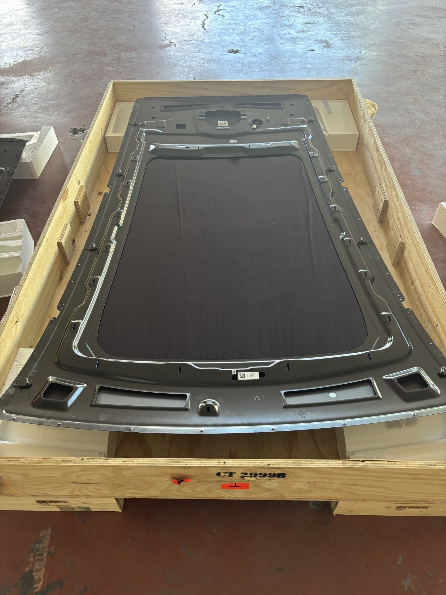 Large metal and black panel strapped inside a wooden shipping crate in a workshop.