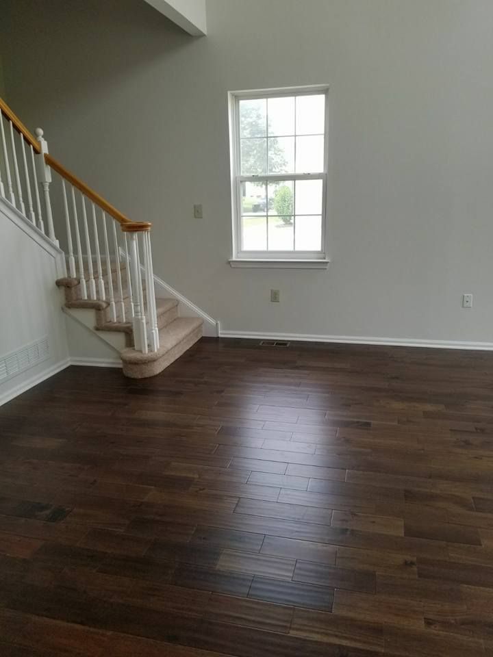 An empty living room with hardwood floors and stairs.