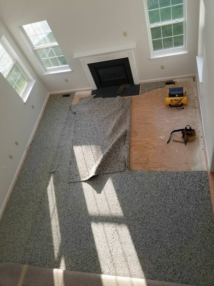 An aerial view of a living room with a fireplace and carpet being installed.