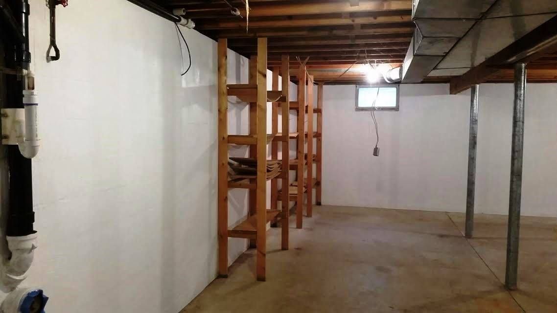 An empty basement with white walls and wooden shelves.