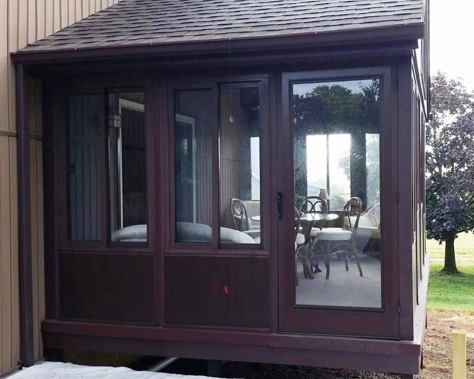 A screened in porch with a table and chairs inside