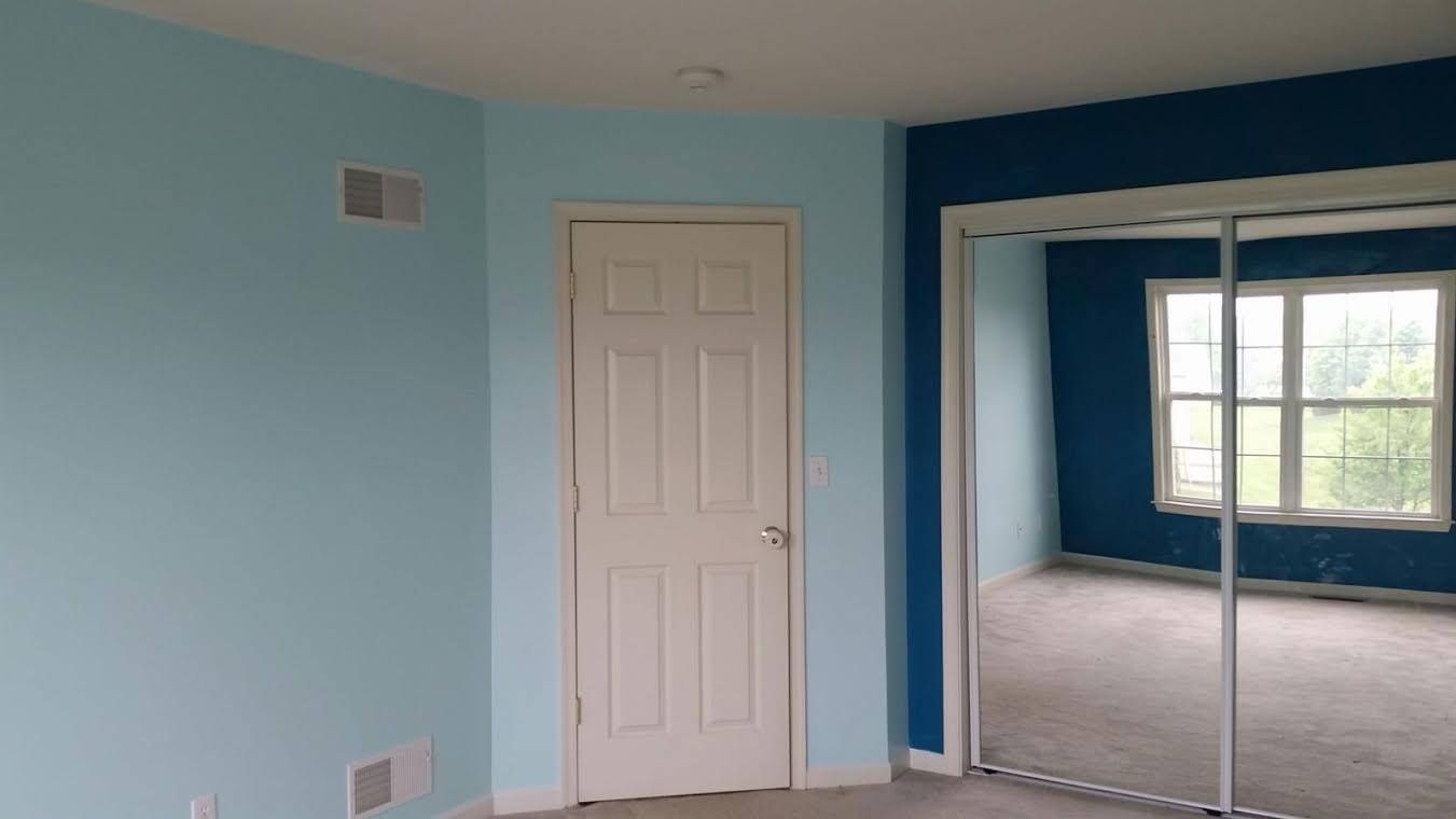 A bedroom with blue walls and a sliding glass door.