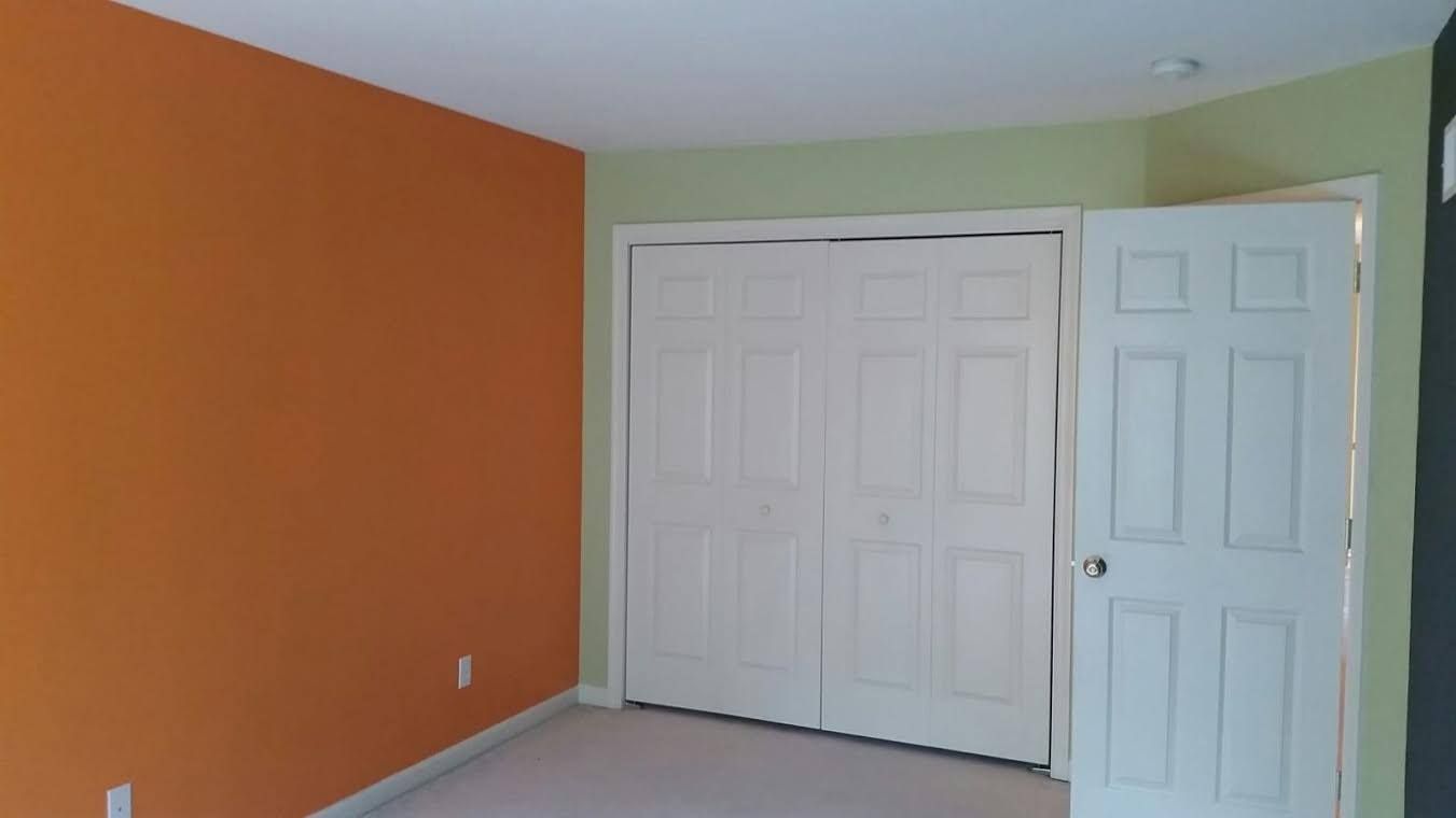The front of a house with blue shutters and a red door.