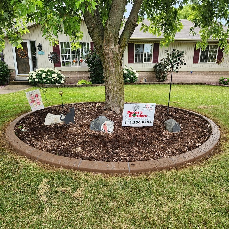 A circular tree bed with mulch, decorative stones, and a