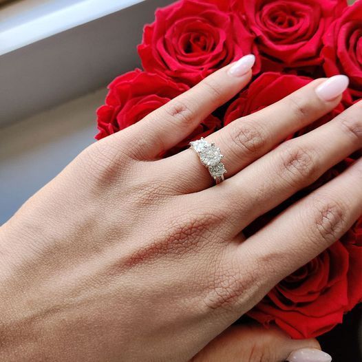 a woman wearing a diamond ring holds a bouquet of red roses