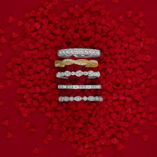 a group of rings sitting on top of a pile of red hearts .