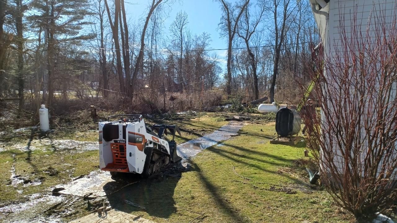 A car is parked in front of a house with a crane in the background.
