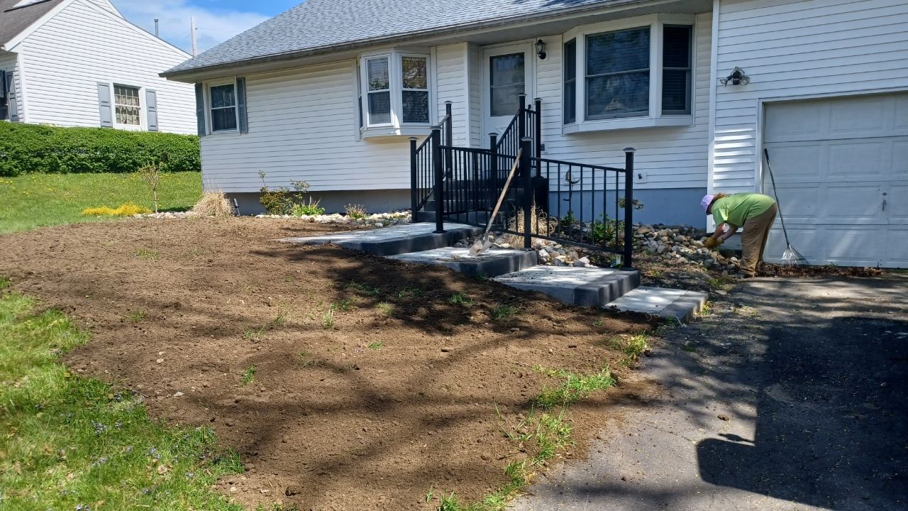 A man is working on a driveway in front of a house.
