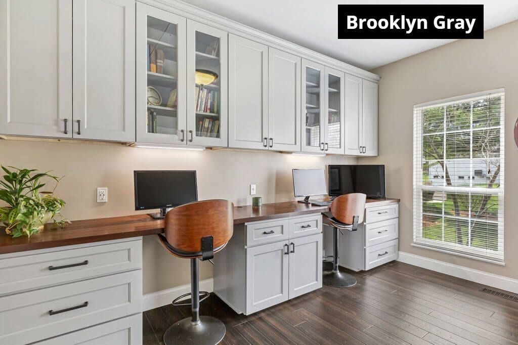 A home office with two desks , two chairs , a computer and a window.