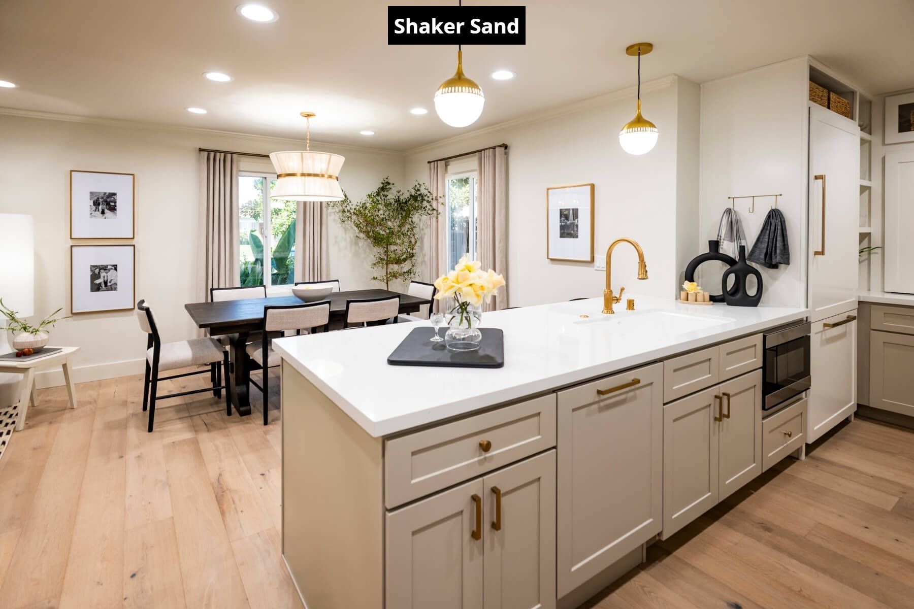 A kitchen with a large island in the middle and a dining room in the background.