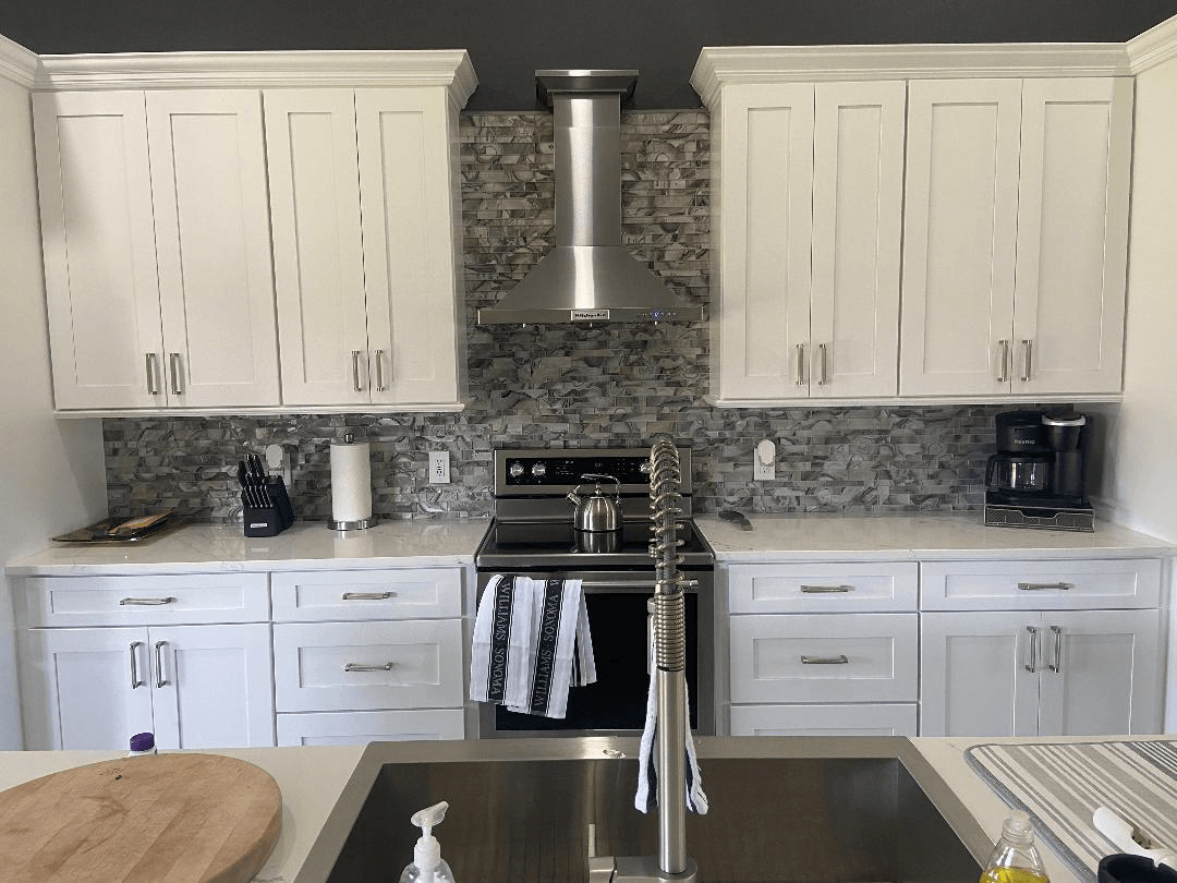 A kitchen with white cabinets , stainless steel appliances , a sink and a stove.
